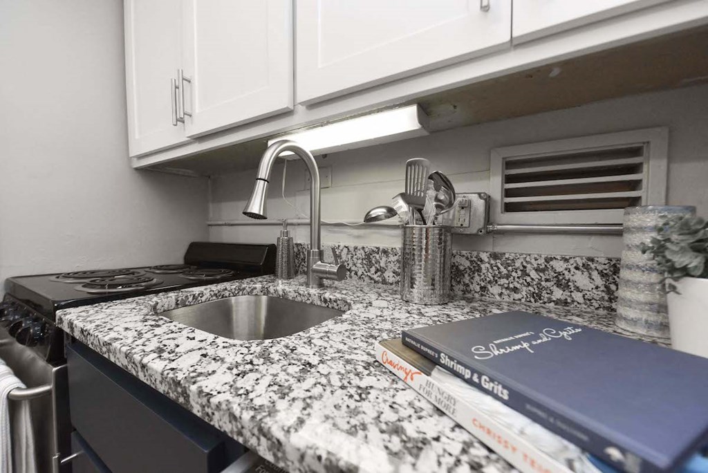 Kitchen with granite countertop, white cabinets, and stainless steel sink