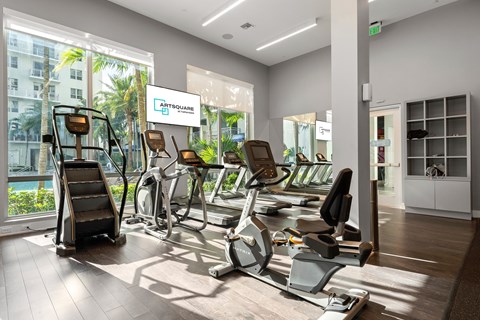 A gym with a variety of equipment including treadmills, stationary bikes, and elliptical machines.