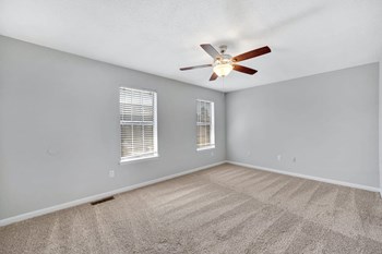 bedroom with illuminated ceiling fan, two large windows, and plush carpet at Goshen Estates - Photo Gallery 8