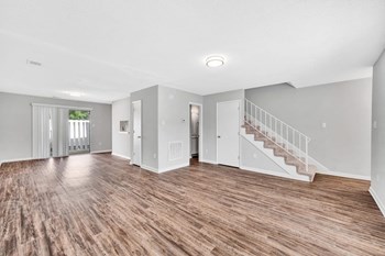 Spacious living room with wood-style flooring, overhead light, and patio access at Goshen Estates - Photo Gallery 7
