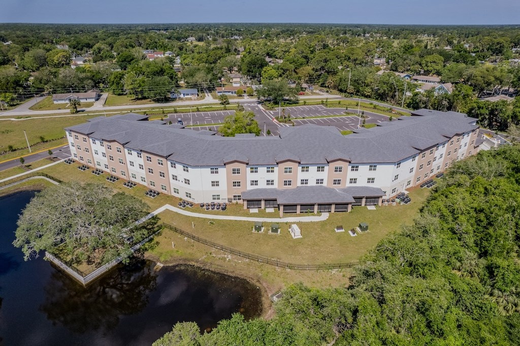 an aerial view of a building surrounded by trees and a body of water