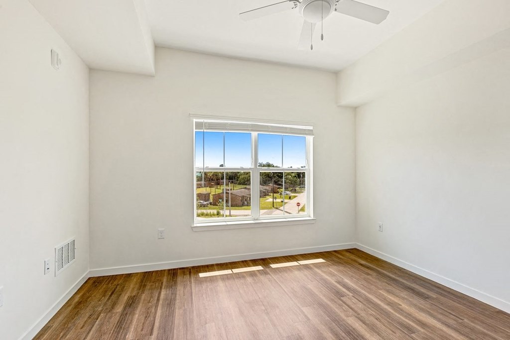 an empty living room with a window and wood floors