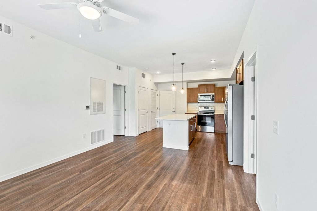 an empty living room with a kitchen in the corner