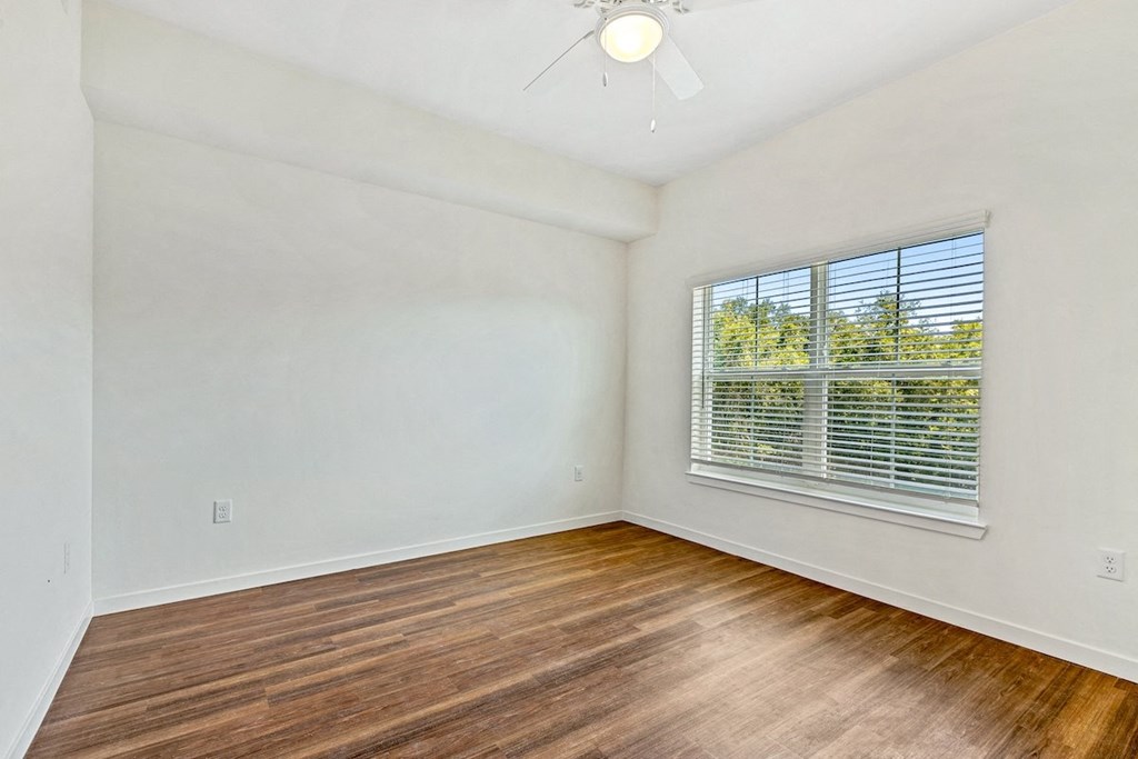 an empty living room with wood floors and a large window