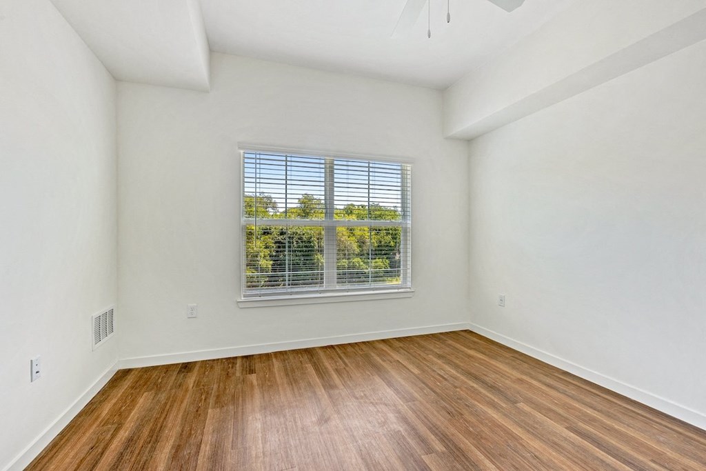 an empty living room with wood floors and a window