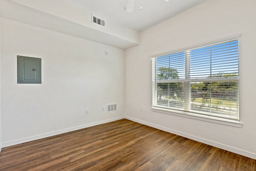 an empty living room with wood floors and a large window