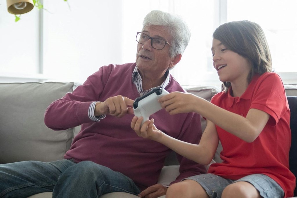 an older man and a young boy sitting on a couch playing a video game