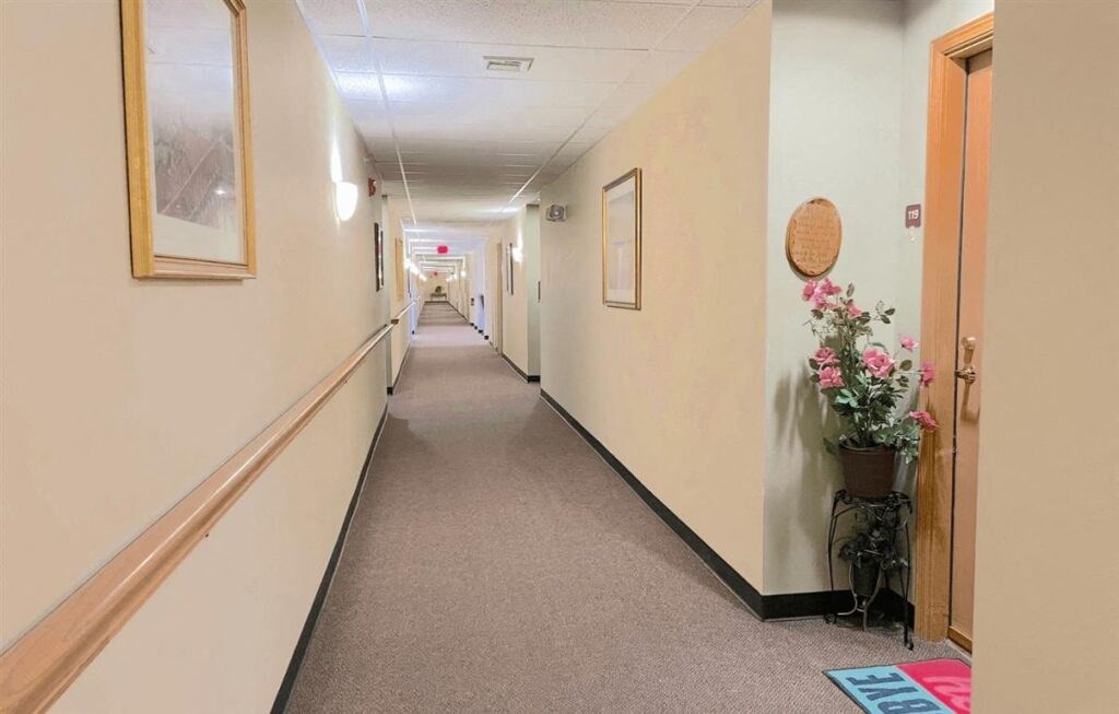 a residential corridor with flowers on the side of an apartment door