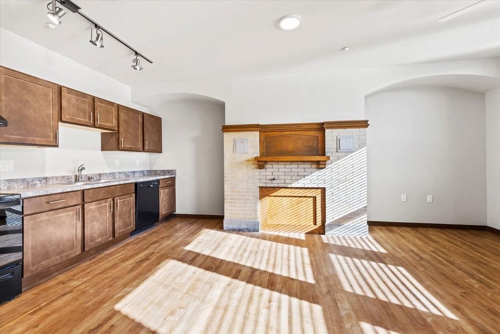 a spacious kitchen with wood cabinets and floors and black appliances at Horicon School Apartments