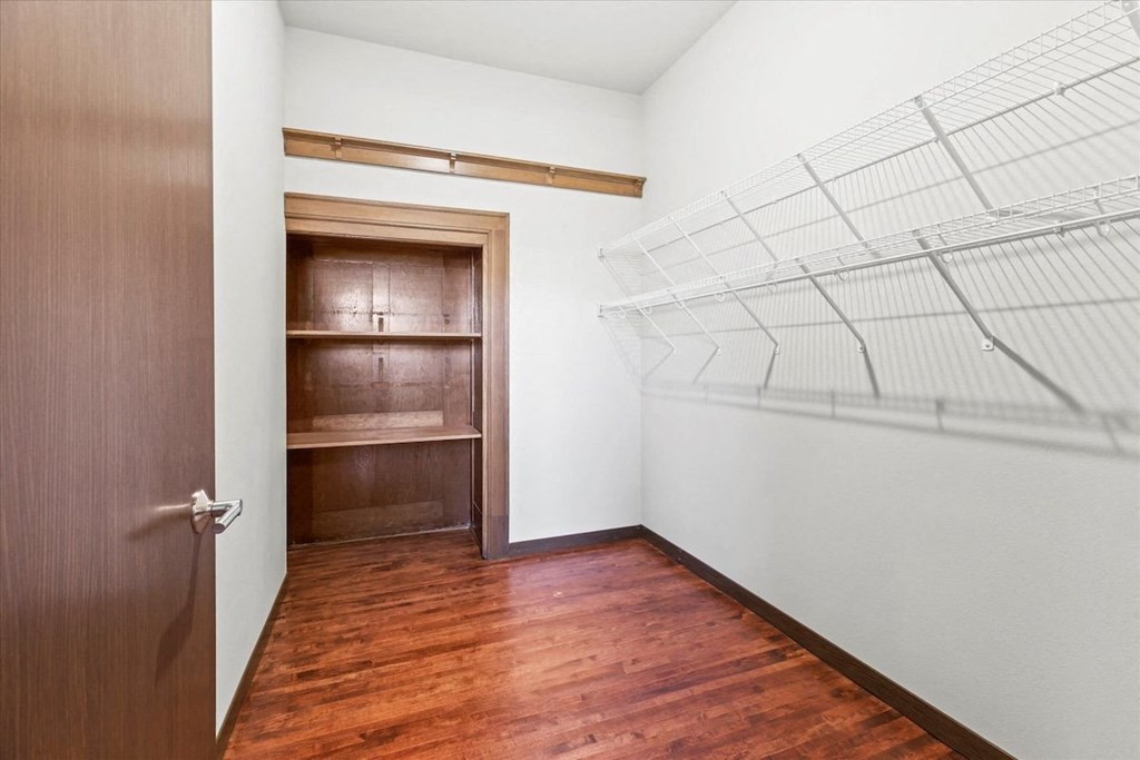 a walk-in closet with built-in shelving and wood flooring