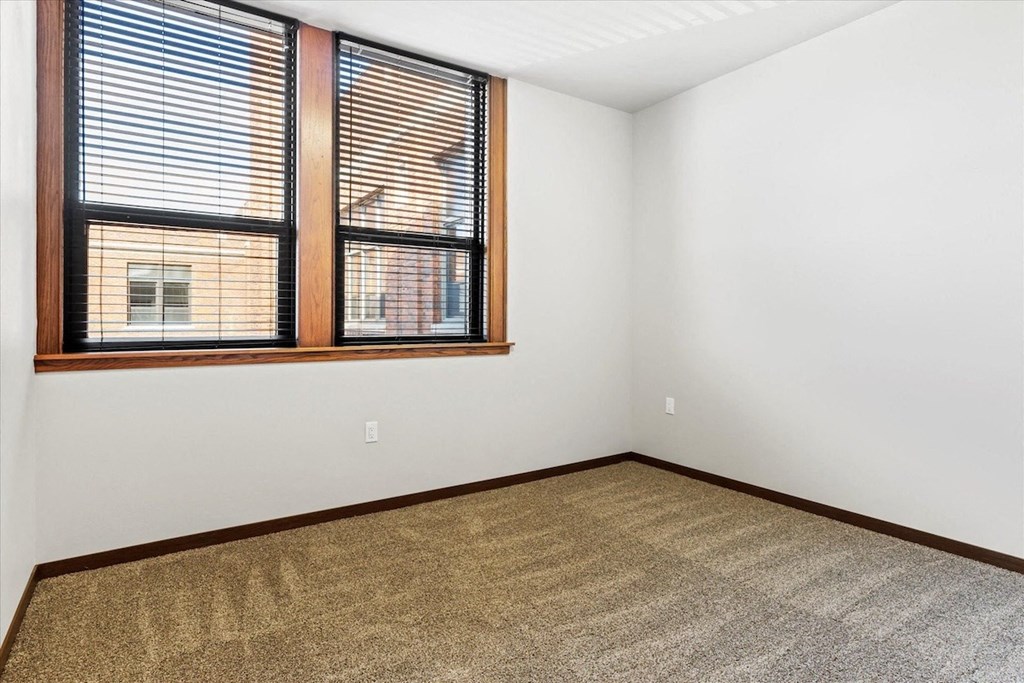 a bedroom with plush carpeting and a large window at Horicon School Apartments