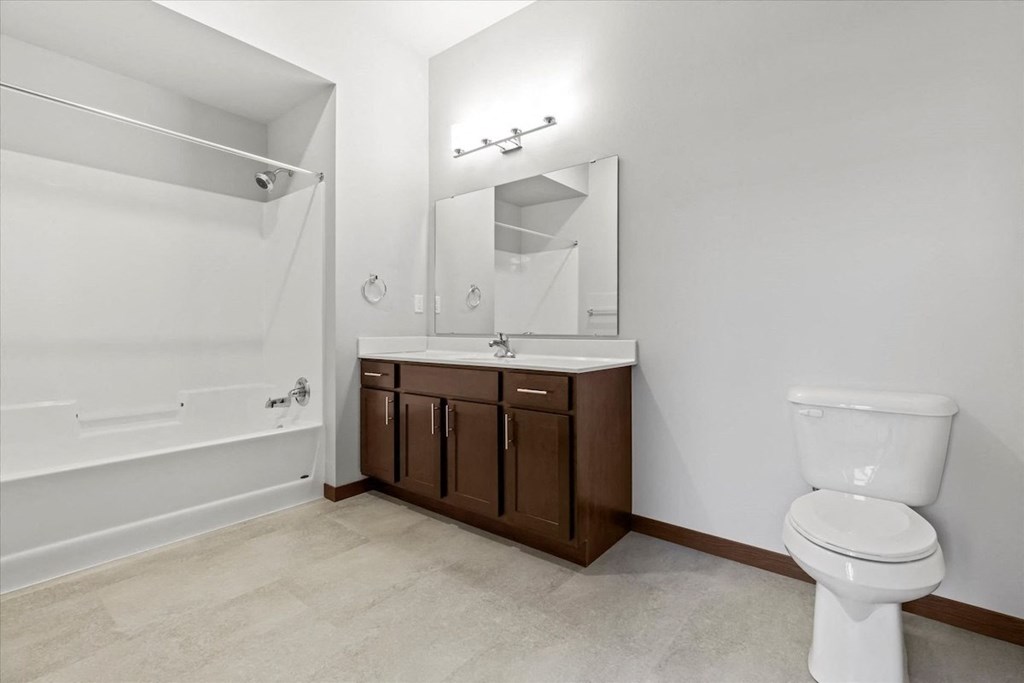 a bathroom with a toilet sink and shower and a mirror at Horicon School Apartments