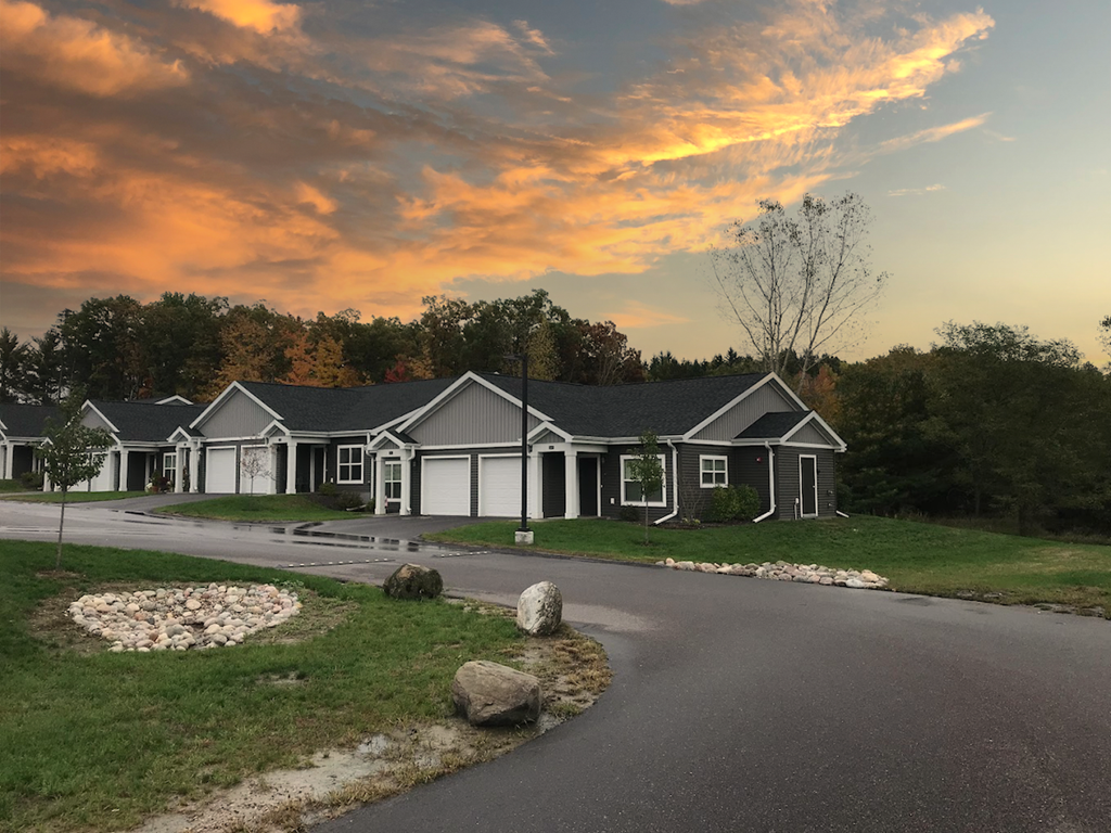 a row of homes with lush landscaping and attached garages at Pioneer Ridge in Wisconsin Dells