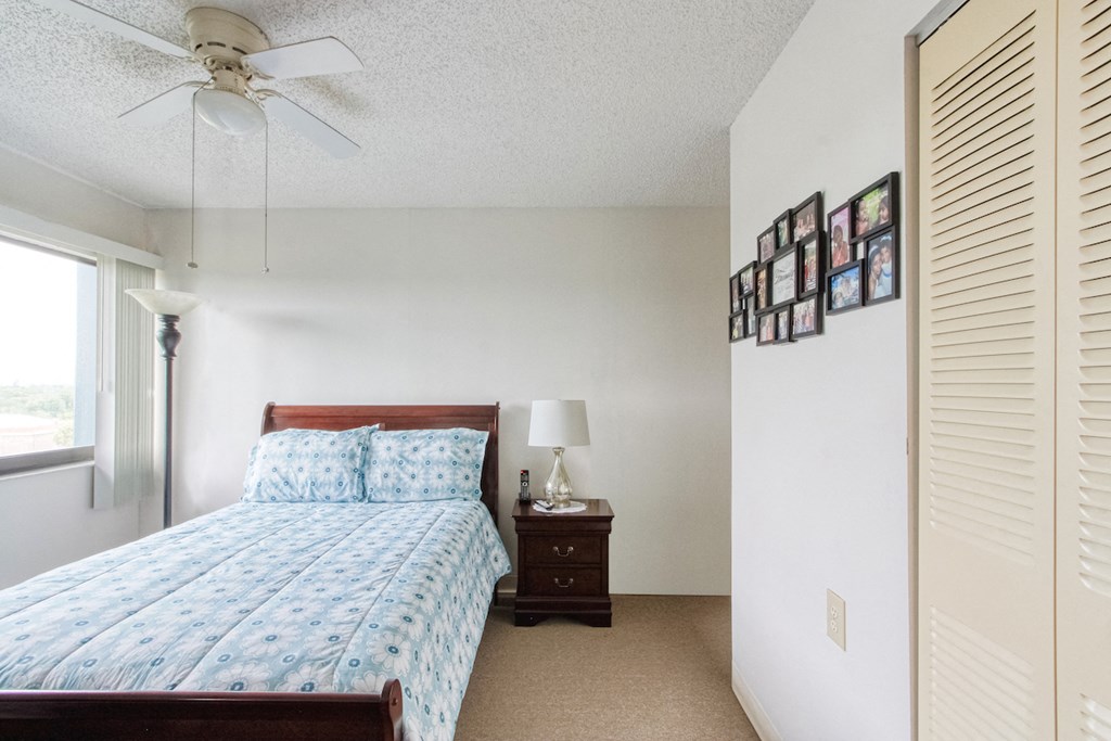 Orlando-Cloisters-14 bedroom with large window, ceiling fan, closet, and model furnishings