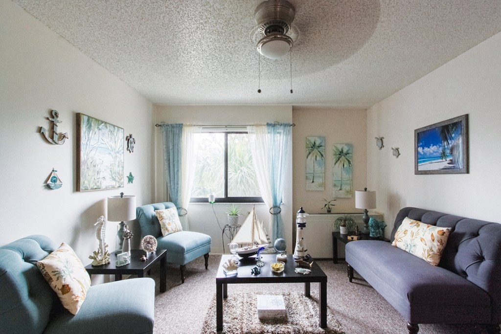 living room with large windows, ceiling fan, and model furnishings at Orlando Cloisters
