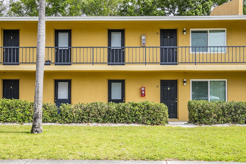 a yellow building with a balcony and a sidewalk