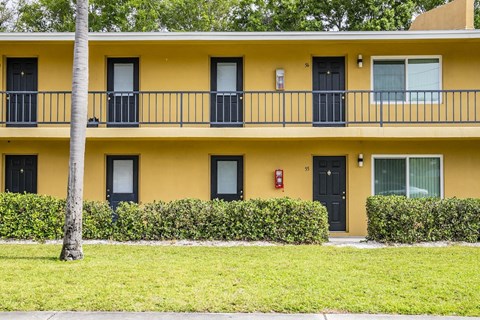a yellow building with a balcony and a sidewalk