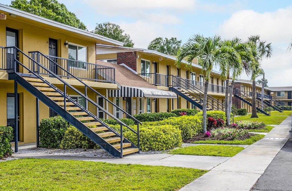 a row of yellow houses with stairs and palm trees