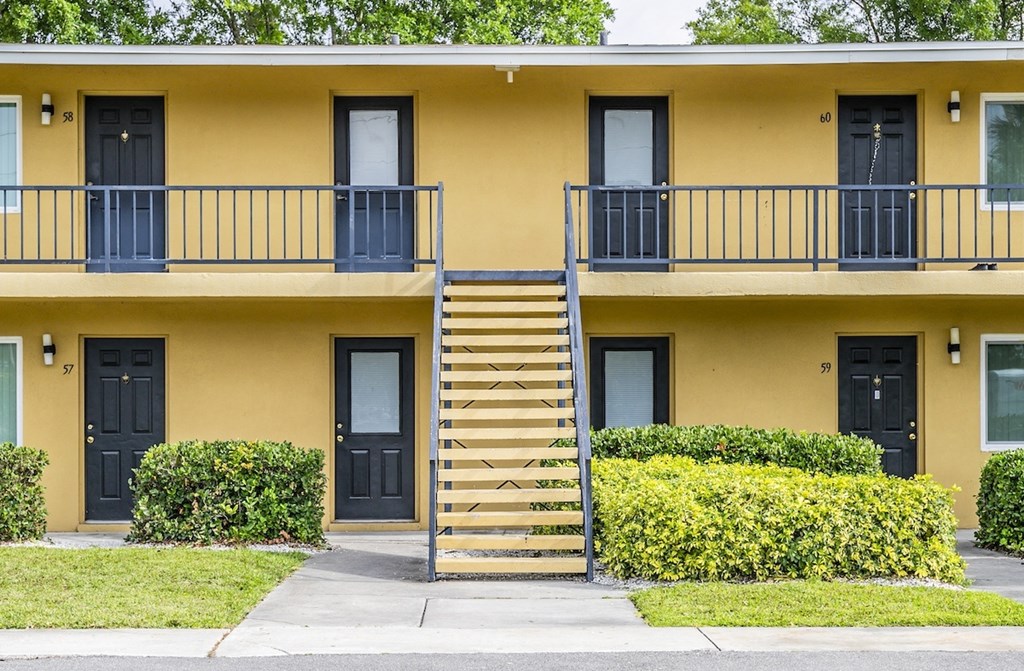 the front of a yellow building with stairs and balconies