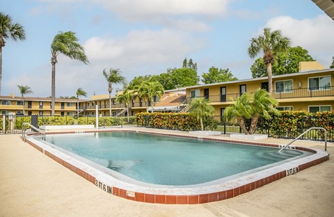 a swimming pool in front of a hotel with palm trees