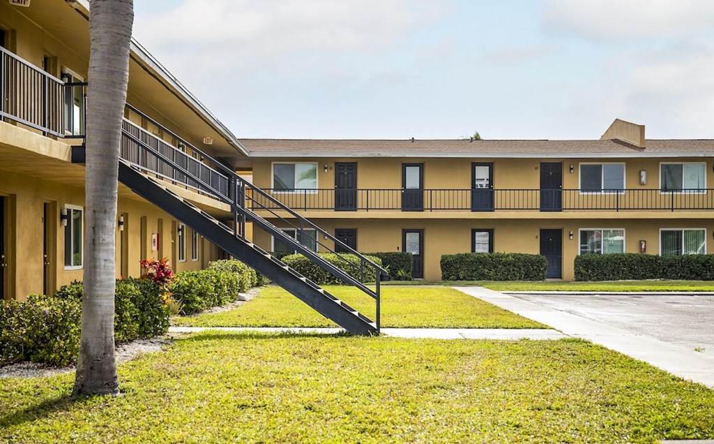 an exterior view of an apartment building with a lawn and a staircase