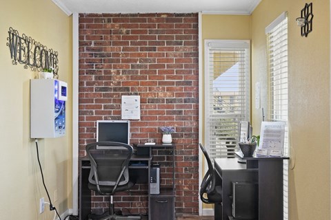 an office with a brick wall and a desk with a computer