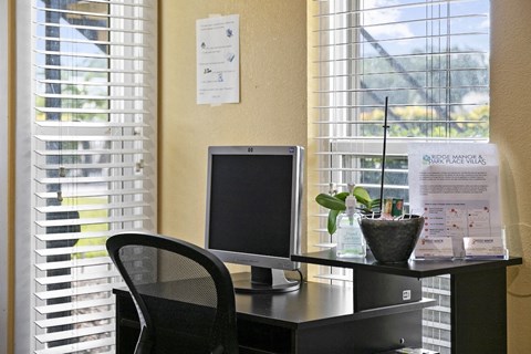 a desk with a computer and a chair in front of a window