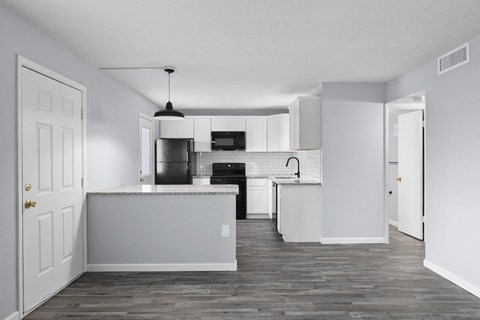 an empty kitchen with white cabinets and a counter top