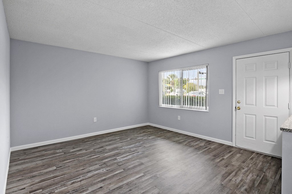an empty living room with wood floors and a window