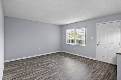 an empty living room with wood floors and a window