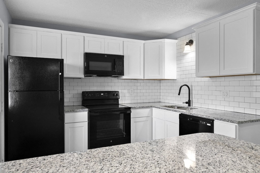 a kitchen with white cabinets and black appliances