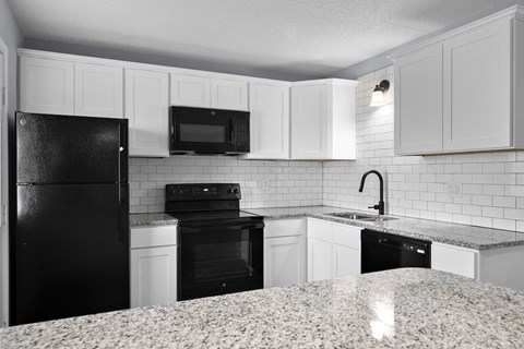 a kitchen with white cabinets and black appliances