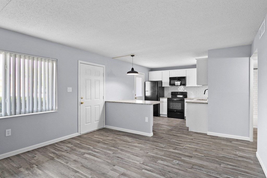 an open kitchen and living room with a wood floor and white walls
