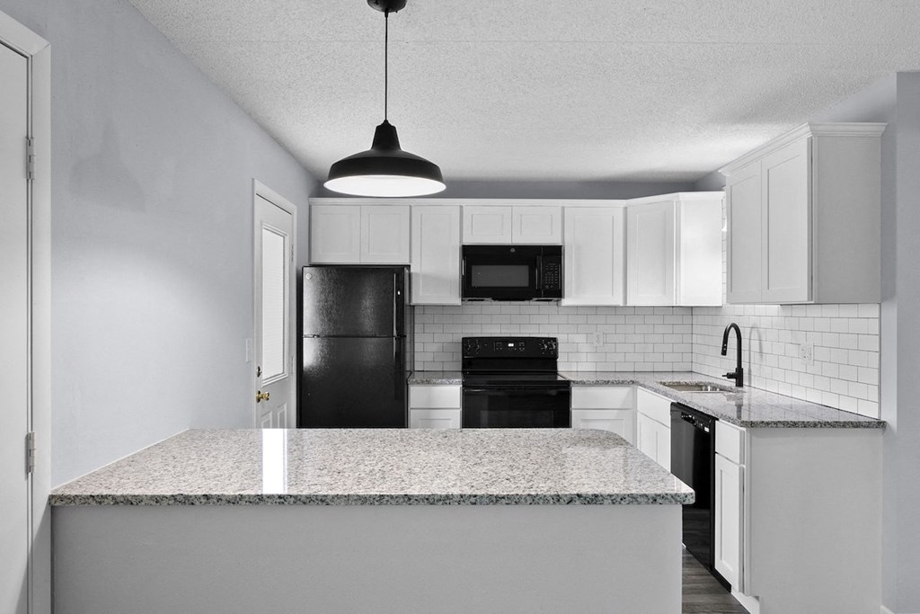 an empty kitchen with white cabinets and black appliances