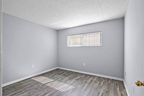the spacious living room with wood flooring and a window