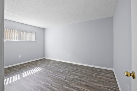 an empty living room with wood flooring and a window