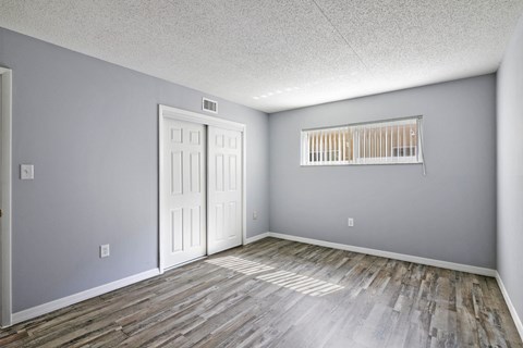 the living room of an empty house with wood flooring and a window