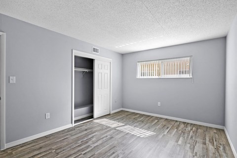 the spacious living room is empty and has a door to the closet