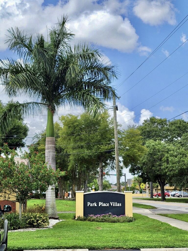 Park Place Villas sign with towering palm tree and lush landscaping