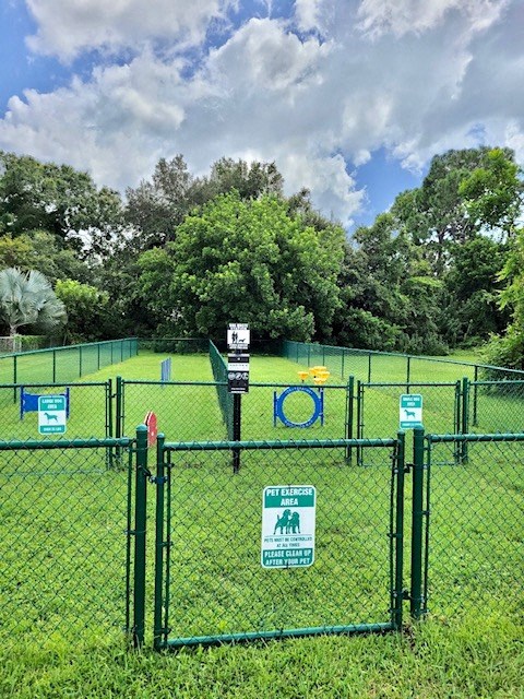 large fenced bark park with agility course