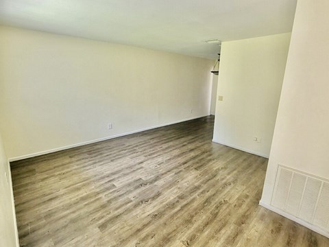 an empty living room with wood flooring and white walls