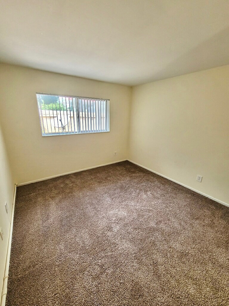 bedroom with plush carpeting and window with vertical blinds