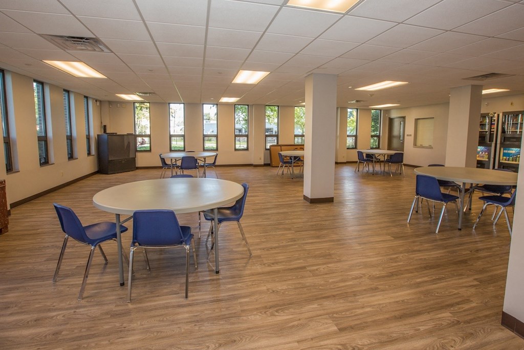 Piotr Stadnitski Gardens community room with tables, chairs, and a large TV