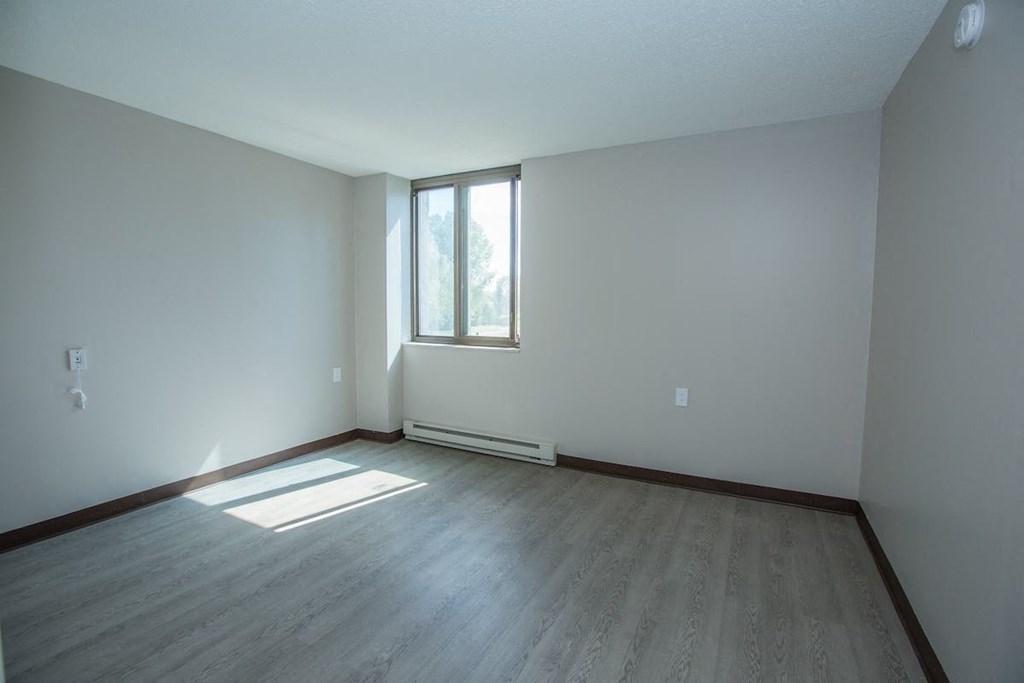 a bedroom with a window and wood-style flooring