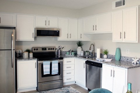 a modern kitchen with stainless steel appliances and white cabinets