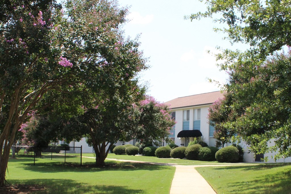 neatly kept sidewalk with mature trees, and neat apartment buildings  at Huntsville Landing Apartments, Alabama