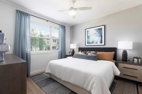 A bedroom with a large bed, a nightstand, and a ceiling fan.