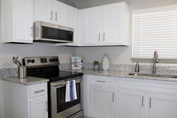 TVA-PG_3 Model kitchen with granite countertops, stainless steel stove, and built-in microwave - Photo Gallery 2