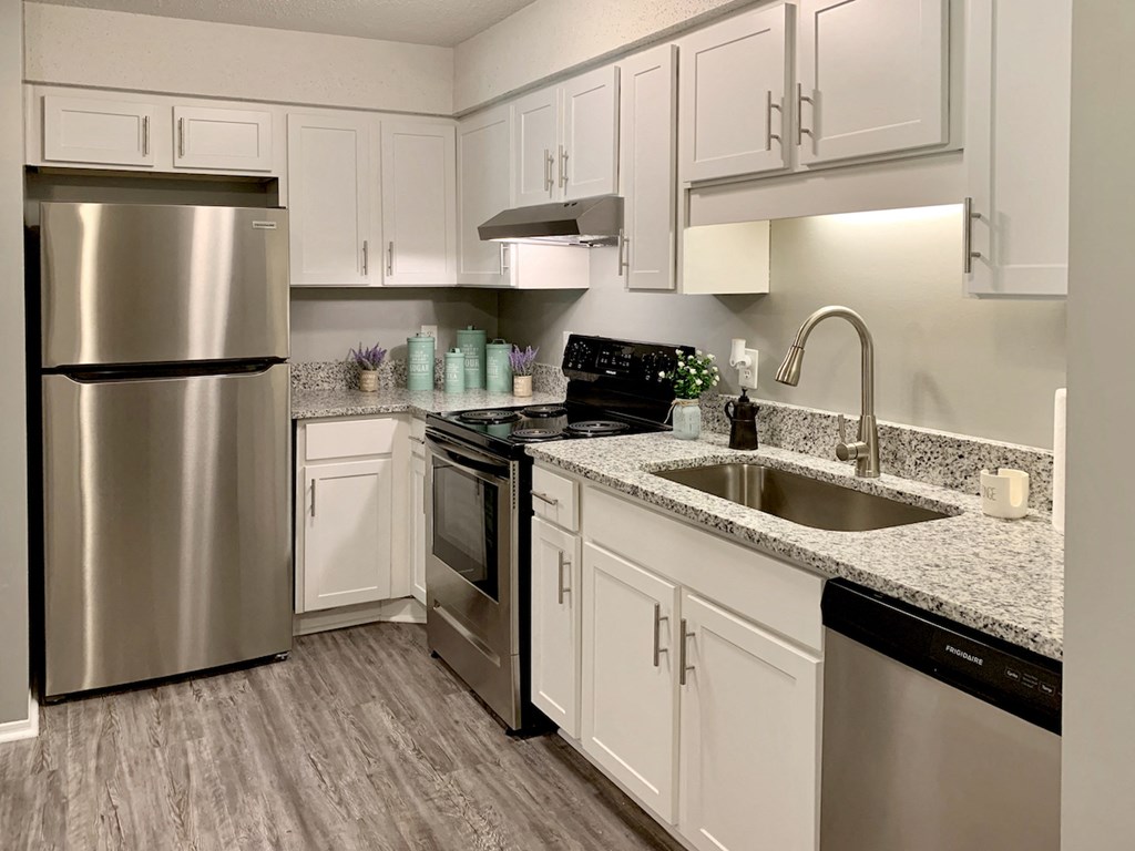 a kitchen with white cabinets, granite countertops, and stainless steel appliances