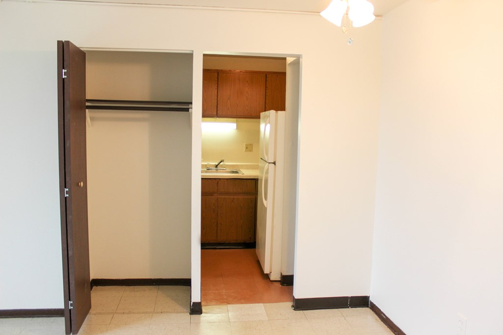 A kitchen area with a refrigerator and wooden cabinets.